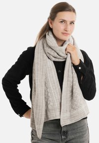 Lichtgrijze sjaal met gestructureerde patronen en subtiele geometrische ontwerpen, gemaakt van zacht materiaal, om de nek gedrapeerd.