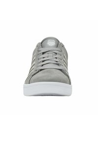 Sivé semišové tenisky s bielymi gumovými podrážkami, vybavené sivými šnúrami, logom na jazyku a troma vertikálnymi pruhmi po stranách.