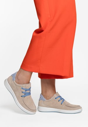 Light beige suede sneakers with blue laces and accents, rounded shape, white sole, and decorative stitching near the upper edge.