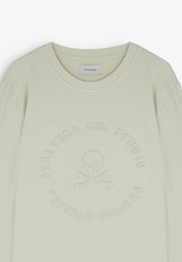 Sweatshirt beige clair à col rond avec crâne et os croisés embossés et texte circulaire "Scalpers Co. Studio Trends Atelier."