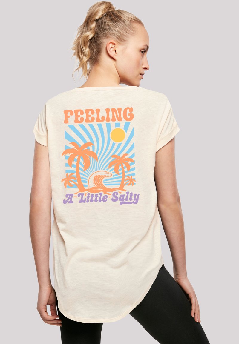Cream-colored short-sleeve t-shirt with a tropical design featuring orange palm trees, blue waves, sunlight, and the text "Feeling A Little Salty."