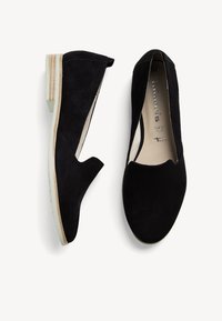 Fekete suede anyagú slip-on cipők alacsony blokk sarkú kivitelben, hegyes orral és kivágott oldalakkal. Diszkrét bézs talppal és tónusos varrással rendelkezik.