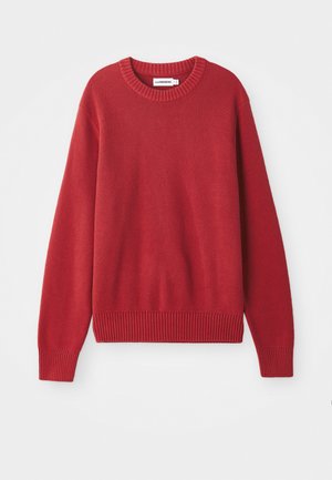 Rød strikket sweater med rund halsudskæring, ribbede manchetter og kant, der har et tekstureret, chunky mønster over det hele.