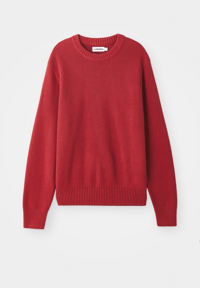 Rdeča pletena pulover s okroglim izrezom, rebrastimi manšetami in robom, ki vsebuje strukturiran, debel vzorec po celotni površini.