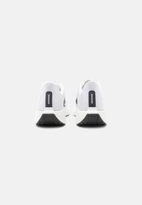 Zapatillas deportivas blancas con parte superior de malla y detalles en negro, forma redondeada, talón acolchado y suela de goma texturizada para mayor agarre.