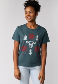 Groen T-shirt met korte mouwen met een witte en rode feestelijke afbeelding van bomen, sneeuwvlokken en een patroonfiguur in het midden.