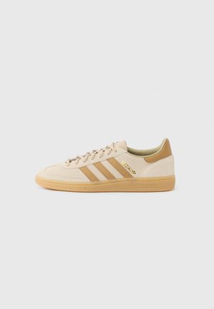 Beige Adidas sneaker med lysebrune striber, gummisål og gyldent "Spezial" tekst på siden, vist fra ydersiden på en hvid baggrund.
