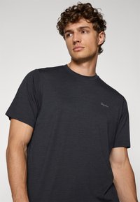 Tricou scurt din material ușor, de culoare gri închis. Prezintă un decolteu rotund și un logo subtil pe piept. Textură fină.