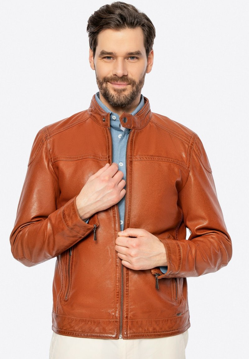 Giacca in pelle marrone con chiusura a zip, dotata di tasche laterali e colletto alto. Texture liscia con dettagli di cucitura delicati.