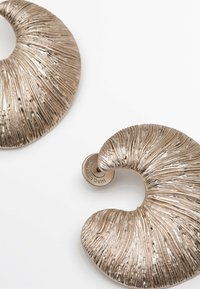 Boucles d'oreilles spirales en métal avec des rainures texturées, présentant une finition bronze brillante. Comprend un fermoir à tige circulaire pour un maintien sécurisé.