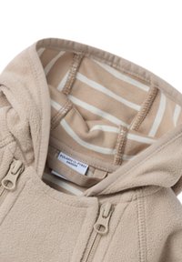 Beige fleece hoodie med foret hætte, der har lyse beige og hvide striber. Inkluderer lynlåse og et mærke, der angiver mærket.