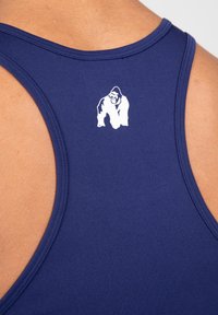 Marineblauw tanktop met een gladde textuur. Heeft een witte gorilla-afbeelding op de bovenrug en een ronde halslijn met schouderuitsparingen.