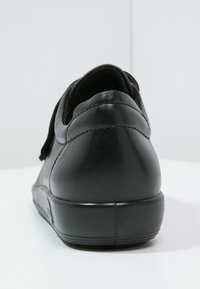 Scarpa in pelle nera con tacco arrotondato, caratterizzata da una texture liscia e da una sottile cucitura lungo la parte posteriore e i lati.