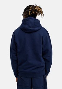 Navy blue hoodie with a relaxed fit, large hood, ribbed cuffs and hem, made from soft cotton fabric, featuring a plain design.
