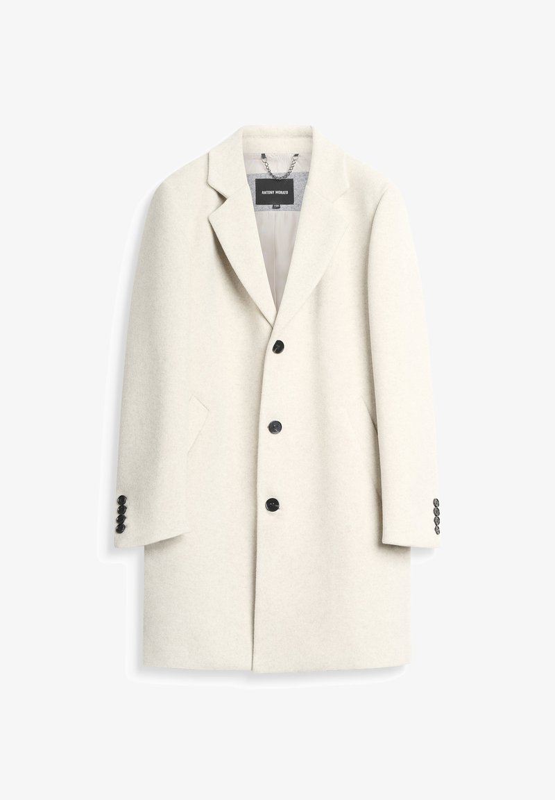 Cappotto in misto lana bianco con rever sagomato, design monopetto, cinque bottoni neri e tasche laterali. Presenta polsini con bottone.