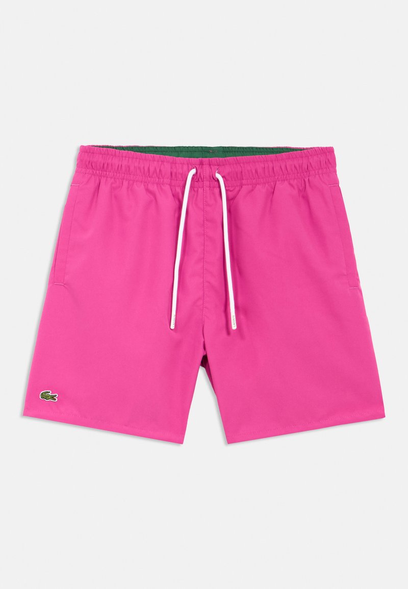 Bañador corto rosa con cinturilla elástica, cordón blanco, bolsillos laterales y forro interior verde. Cuenta con un pequeño logo en el bajo.