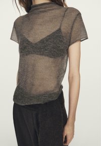 Doorzichtig bruin gebreid bovenstuk met een aangesloten onderlaag. Korte mouwen en een hoge halslijn. Zachte textuur met een gelaagd effect.