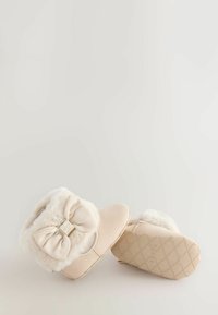Tanfarbene Stiefeletten mit Kunstfellbesatz und einer großen Schleife. Strukturiertes Gummiband mit einem Diamantmuster. Weiches, samtartiges Material.