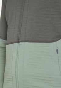 Grijze en mintgroene trui met een gladde textuur, met een contrasterend horizontaal ontwerp en een ritsdetail aan de zijkant.