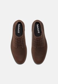 Chaussures en cuir marron avec bouts ronds, design à lacets et finition texturée. Elles disposent d'un col rembourré et d'un logo sur la semelle intérieure.