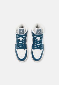 Paire de baskets montantes blanches et bleues avec lacets bleu foncé, embouts perforés, et logo "Air" sur les languettes rembourrées, vues de dessus.