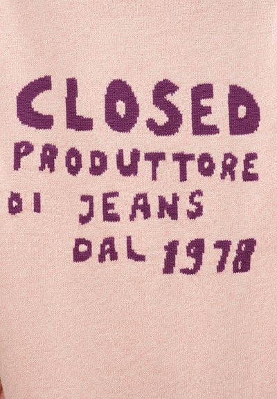 Κείμενο «CLOSED PRODUTTORE DI JEANS DAL 1978» πλεκτό με μοβ χρώμα σε ροζ φόντο υφάσματος.
