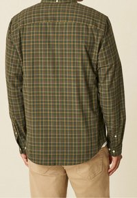 Groen en bruin geruit overhemd met lange mouwen, knoopkraag en rechte zoom, voorzien van witte knopen bij de manchetten en de achterpas.