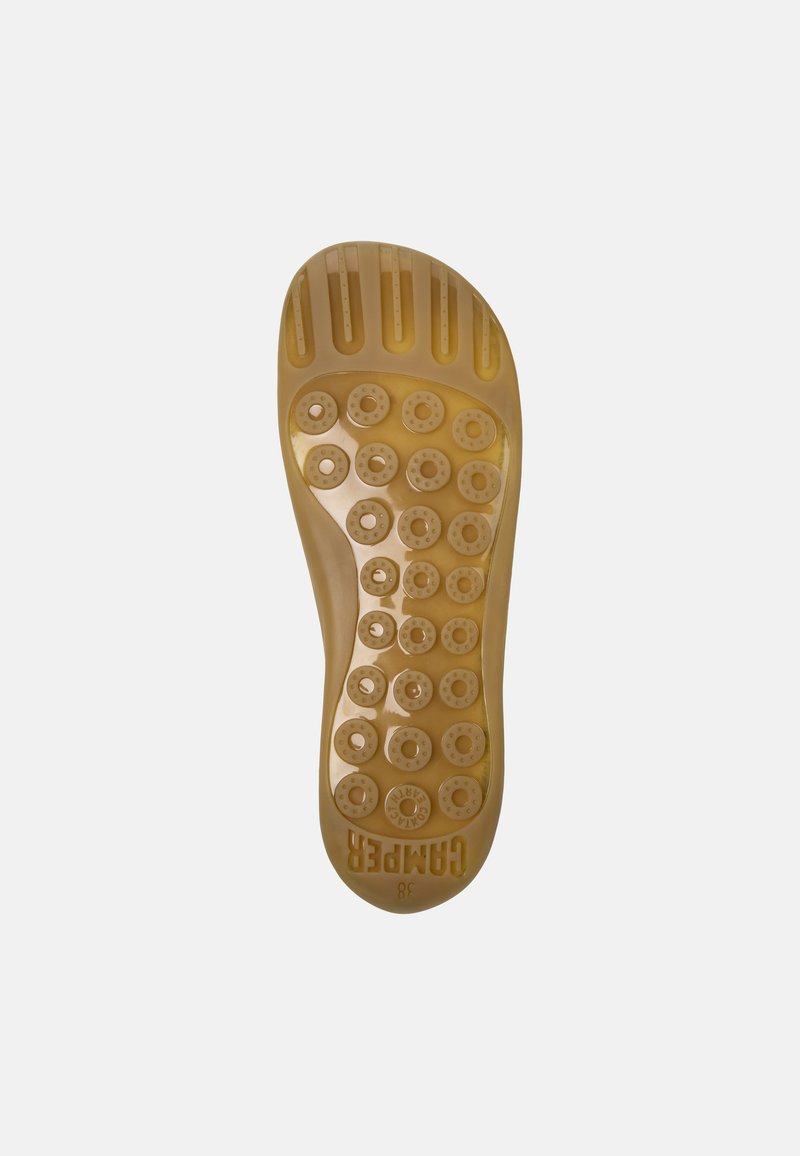 Translucent rubber shoe sole in light tan, featuring raised circular grips and rectangular grooves for traction; size printed.