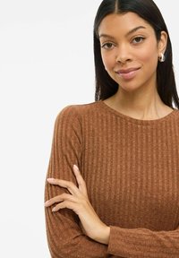 Brūns ribotais garām piedurknēm tops ar apaļu kakla izgriezumu. Audumam ir tekstūras izskats, ko papildina smalkas detaļas uz piedurknēm.