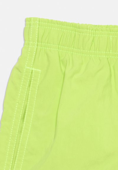 Λαμπερά πρασινά σορτς με ελαστική μέση, εμφανή λευκή ραφή και κάθετη ραφή πλαϊνής τσέπης.