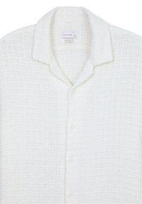 Chemise blanche texturée en maille gaufrée, coupe décontractée, col et boutons sur le devant, taille indiquée large, marque Calliope.