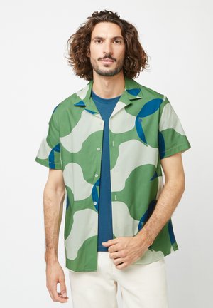 Camicia a maniche corte verde e bianca con motivi astratti blu e verdi. Caratterizzata da un frontale con bottoni e un colletto piatto.