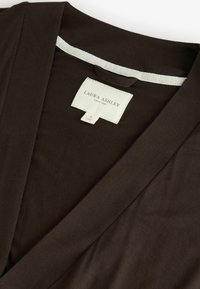 Ruda surišta viršutinė dalis, pagaminta iš minkštos medžiagos, su V formos dekoltė, etikete su "Laura Ashley" ženklu ir lygiu paviršiumi.