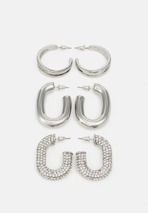 Four pairs of silver earrings: two shiny smooth hoop designs, one textured, and one covered in small clear rhinestones.