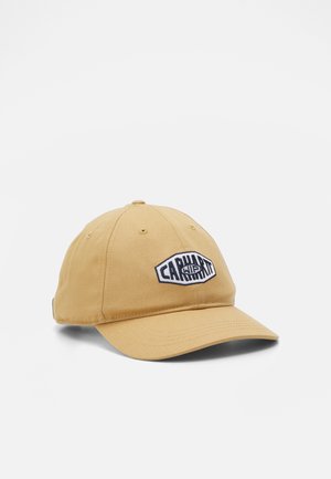 Beżowa czapka baseballowa Carhartt WIP z zakrzywionym daszkiem i czarno-białą naszywką z logo z przodu, przedstawiona na jednolitym tle.