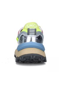 Scarpa sportiva con tomaia in rete argentata, dettagli verde neon e suola in gomma blu. Presenta un colletto imbottito e una suola con grip testurizzato.