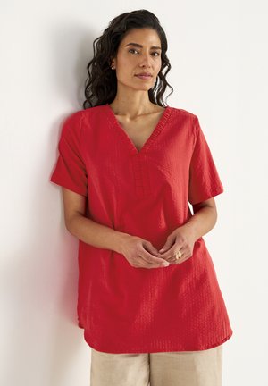 Rød kortærmet top med V-hals, tekstureret stof og lodrette syninger. Lavet af et let materiale, skræddersyet til en løs pasform.