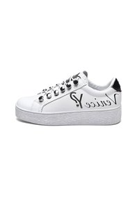 Sneaker bianca con suola piatta testurizzata, borchie metalliche sui lacci e dettagli neri sul tallone e sul lato. Presenta il logo sul lato esterno.