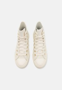 Hohe Sneaker aus cremig-weißer Leder mit goldenen Ösen, runder Zehenpartie, flachen Schnürsenkeln und strukturierten Details an den Seiten.
