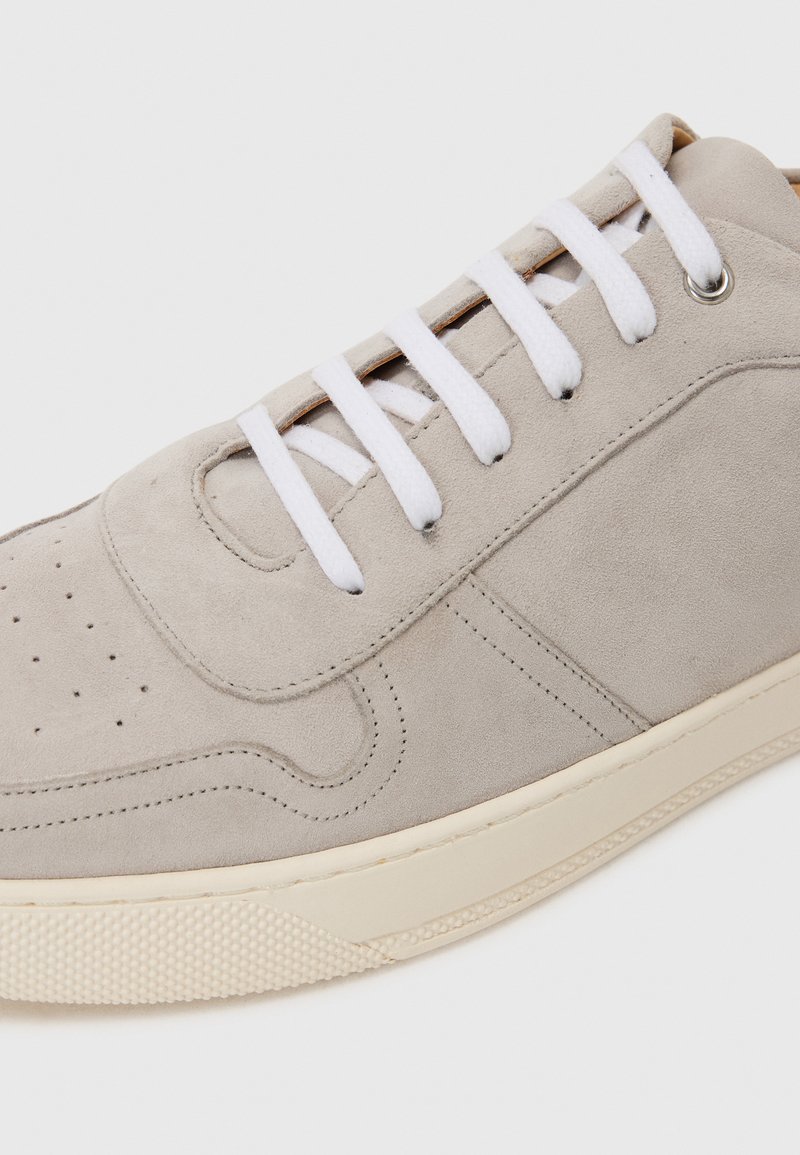 Baskets en nubuck gris avec lacets blancs, boîte à orteils perforée et semelle en caoutchouc. Présente des accents cousus et un design minimaliste.