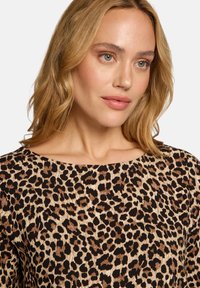 Oberteil mit Leopardenmuster, weitem Ausschnitt, weicher Textur und einer Mischung aus Hellbraun, Dunkelbraun und Schwarz.