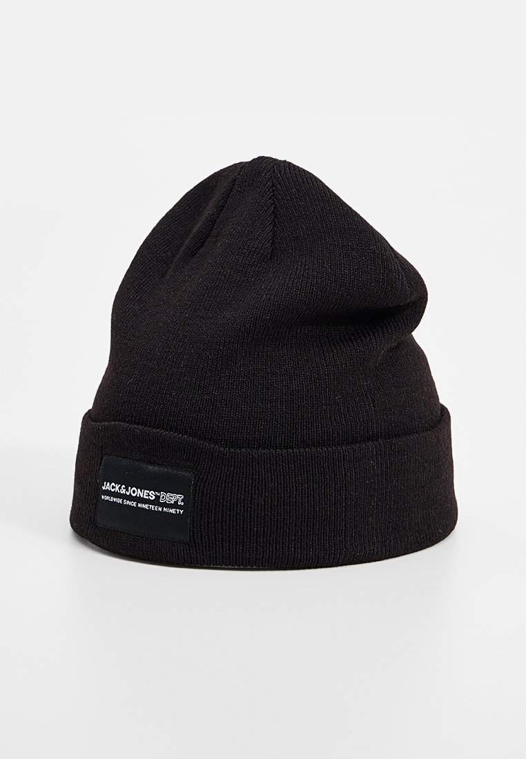 Czarna dzianinowa czapka beanie z złożonym mankietem i prostokątną metką z białym tekstem. Gładka tekstura, zaokrąglony kształt na górze.