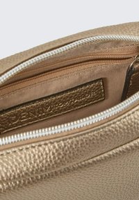 Borsa a pochette con texture dorata e chiusura con zip. Presenta una fodera interna beige e un'etichetta in pelle con marchio visibile all'interno.