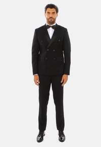 Completo formale nero a doppio petto con rever in satin, camicia bianca, papillon nero e scarpe eleganti nere lucide. Vestibilità su misura e texture liscia.