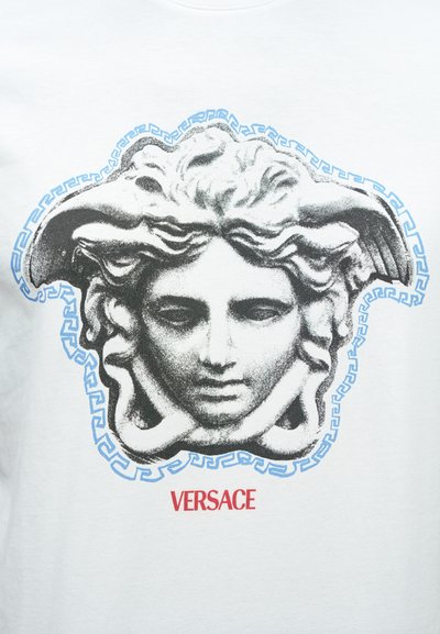 Valge puuvillane T-särk, millel on must-valge Meduusa graafika sinise kreeka võtmepatrrooniga ääristatud ja allpool punase tekstiga "VERSACE".