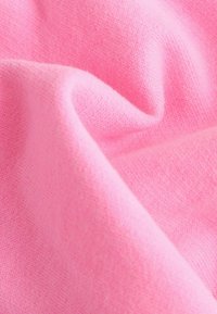 Tissu rose doux avec une texture lisse ; légèrement froissé, affichant de fins motifs tricotés et une couleur uniforme tout au long.