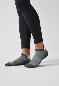 Graue und schwarze Knöchelsocken mit geometrischen Mustern, weicher Textur, verstärkter Zehen- und Fersenbereich sowie kontrastierendem weißen Akzent am Bund.