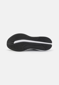 Semelle de chaussure en caoutchouc noir avec des motifs texturés, dotée d'une semelle intermédiaire blanche et d'un design épuré pour l'adhérence et le soutien.