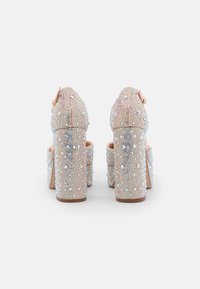 Sandales à talons hauts avec un talon épais, recouvertes de strass irisé et d'une base nude, dotées d'une sangle à l'arrière et d'un design à bout ouvert.