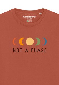 Roestkleurig T-shirt van katoen, met een grafisch ontwerp van maanfasen in oranje, geel, groen en blauwe accenten en de tekst "GEEN FASE."